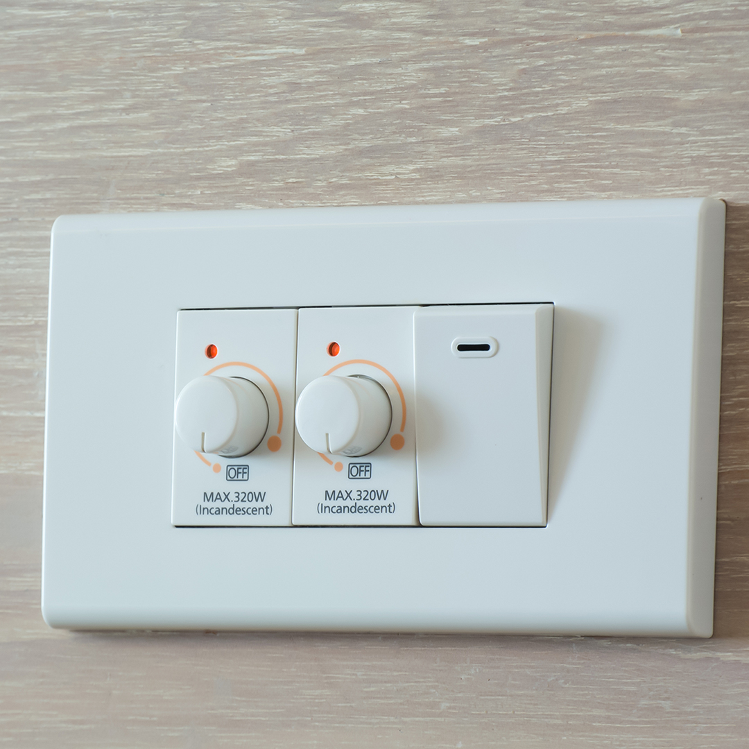 Two dimmer knobs next to a white light switch