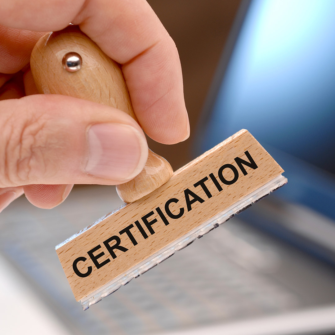 Person holding a wooden stamp that says certification